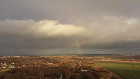 A long road passes through green fields over which low gray clouds float through Stock Footage 275091402
