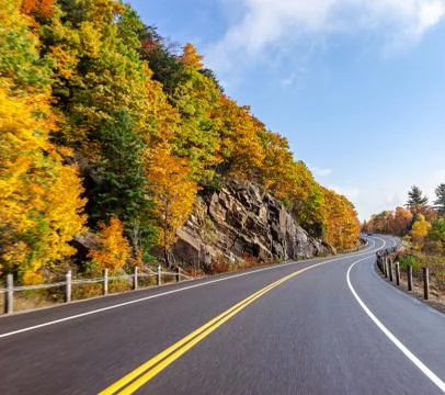 Long road trip empty winding road lined by trees in Algonquin Provincial Park Stock Photos