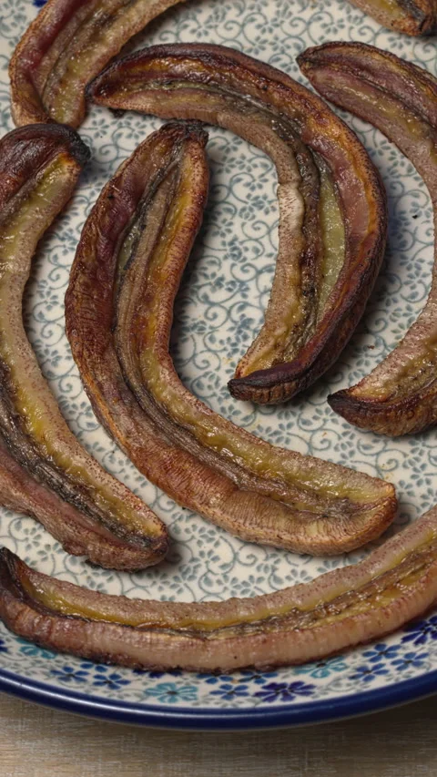 Long roasted bananas on a plate. Vertical video. Stock Footage 308254885