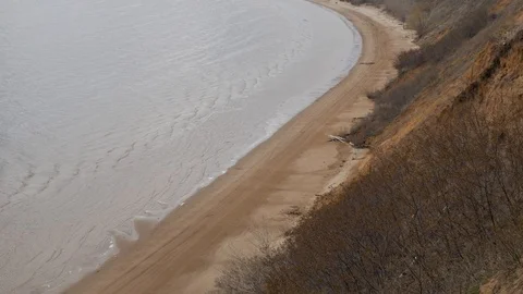 A long rounded strip of sandy shore with small flowing waves of a large beau Stock Footage 128801509
