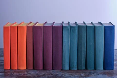 A long row of bright smart thick books in fabric multi-colored covers on an o Stock Photos