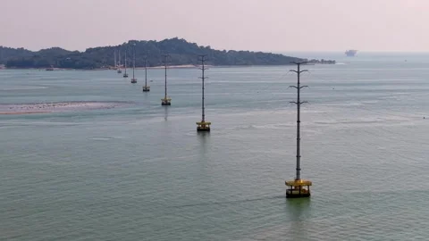 Long row of electrical transmission towers emerging from calm ocean water 스톡 동영상 336882797