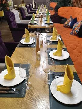 A long row of elegantly set tables in a bright restaurant interior Stock Photos