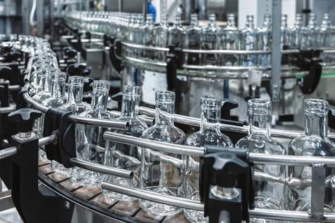 Long row of empty glass bottles for alcohol drinks at plant Stock Photos