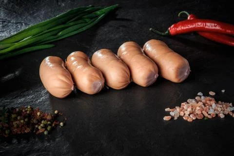 Long row of five raw short thick sausages with chili and onion Stock Photos