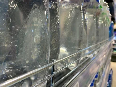 Long rows of bottles of drinking water on the shelf of a convenience store Stock Photos