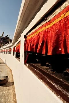 Long rows of prayer wheels covered by red curtains are built into the outer w Foto stock
