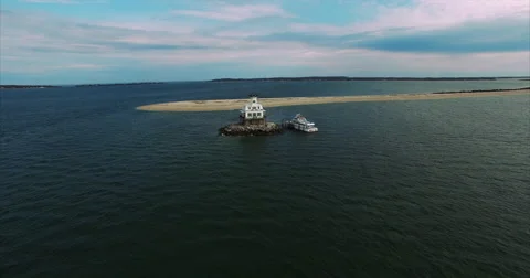 Long sand point running out to a small white lighthouse 動画素材 62147068