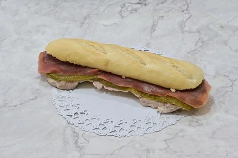 A long sandwich with ham and pickles on a white napkin Stock Photos
