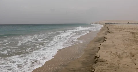 A long sandy beach with sand dunes entering the sea Stockbeeldmateriaal 122016232