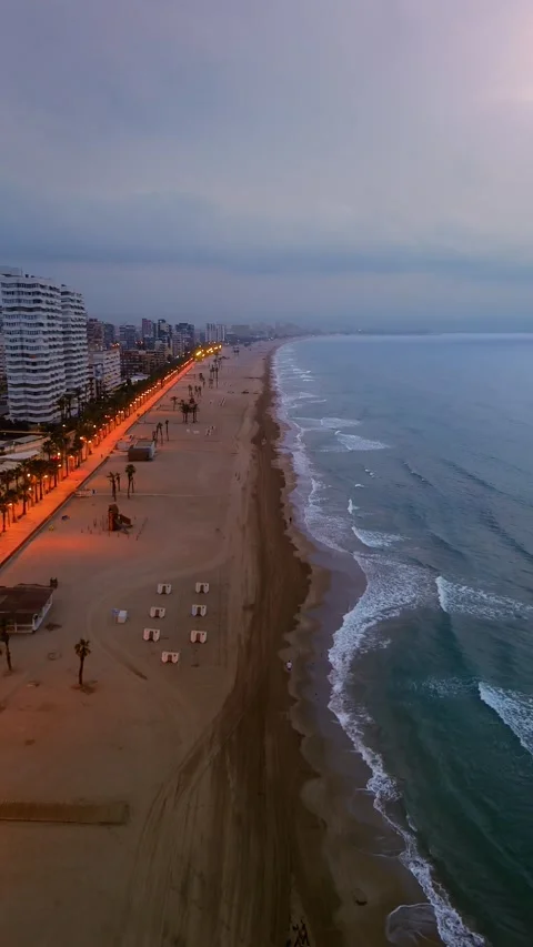 Long sandy beach with waves and beachfront buildings, drone aerial view 動画素材 311620826