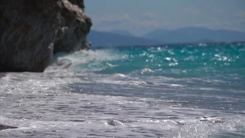Long sea waves with foam on the beach near the huge rock at sunny day. Stock-Footage 157483698