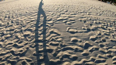 Long Shadow of a girl walking on the beach in the afternoon Stock Footage 100220199