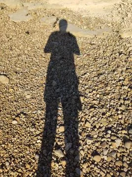 Long shadow of the man standing on the sandy beach Foto stock