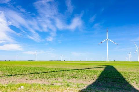 Long shadow under windmill, large wind power turbines spinning to generating Stock Photos
