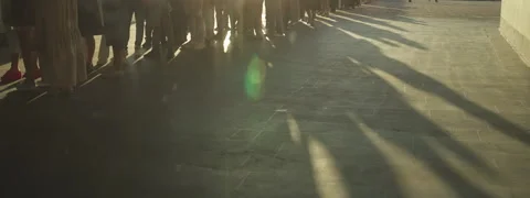 Long shadows on ground cast by very long queue of unrecognizable people Stock Footage 252302634