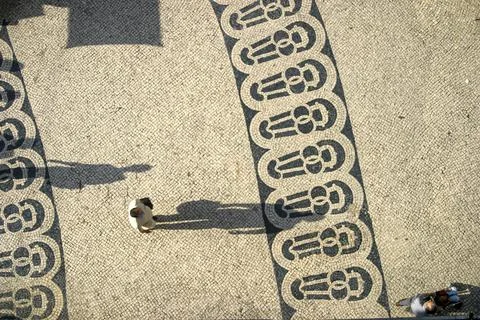Long shadows of people on a square with pattern of paving stones in Lisbon ph Stock Photos