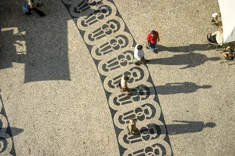 Long shadows of people on a square with pattern of paving stones Stock Photos