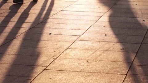 Long shadows of people walking on the sidewalk at sunset Stock Footage 28256828