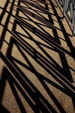 Long shadows from a railing form the unique pattern on a textured ground Stock Photos