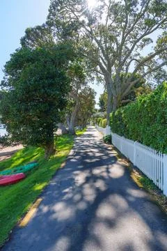 Long shady path vertically composed lined with white picket fence at Russell Stock Photos