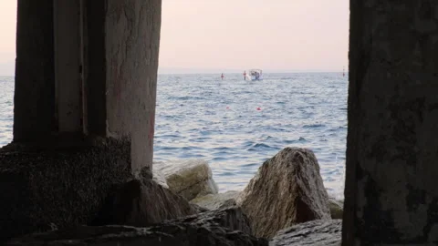 Long shot of a boat at sea seen through a row of pillars at dusk Video stock 248558853