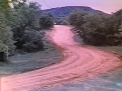 Long shot of car driving down country road, 1970s Stock Footage 65860190