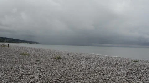Long-shot of Dark stormy clouds over stone beach in UK. Stock Footage 247125931
