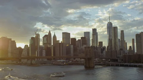 Long shot ferry passing under Brooklyn Bridge leaving Manhattan at sunset Stock Footage 99034559