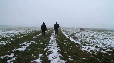 Long shot-figures walking away in snowy field Subclip Stock Footage 1049758