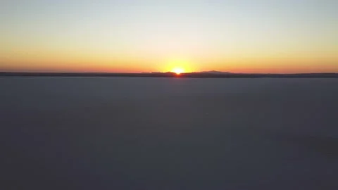 Long shot of flying away from sunset over salt flat lake Stock-Footage 169477246
