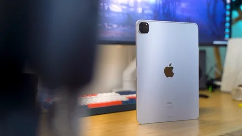 Long shot of full silver iPad Pro standing on desk, cables in foreground Stock-Footage 129153948