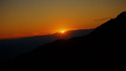 A long shot of the landscape during sunset, with the sun setting behind hills Stock-Footage 282009903