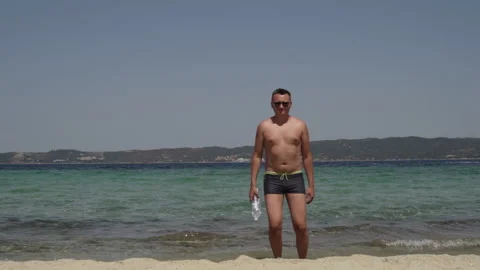 Long shot of a man having fun at the beach. Man in sunglasses, in swimsuit Stock Footage 147948354