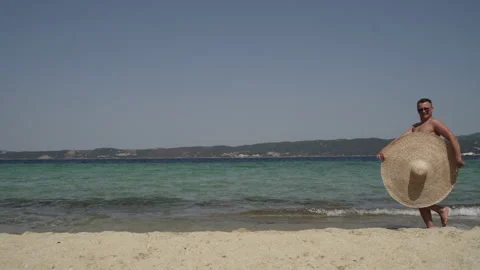 Long shot of a man having fun at the beach. Man in sunglasses with big summer Stock Footage 147948649