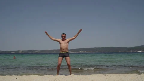 Long shot of a man having fun at the beach. Man in sunglasses, in swimsuit Stock Footage 147948933