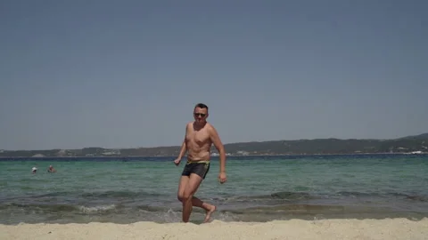 Long shot of a man having fun at the beach. Man in sunglasses, in swimsuit Stock Footage 147949045