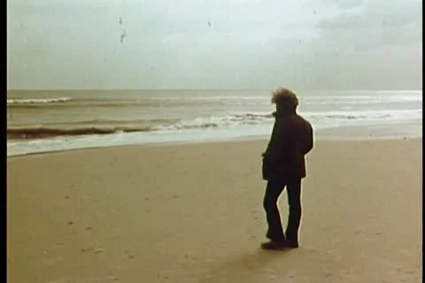 Long shot of man walking  on beach Stock Footage 11346159