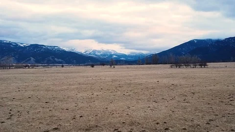 Long shot over empty field toward mountain range Stock Footage 124927259
