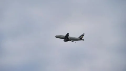 Long shot, passenger plane approaching to land. Airliner flies in cloudy gray Stock Footage 246390176