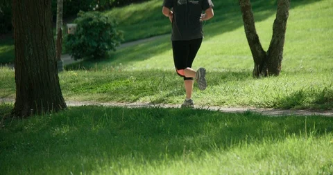 Long shot of running jogging through park Stock Footage 94345663