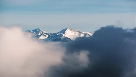 Long shot of snow-capped mountain peaks, shrouded in clouds Stock Footage 230719318