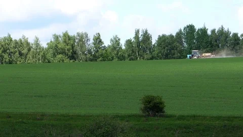 Long shot of a tractor working in in a field, compressing the grass in russia Stock Footage 76174667