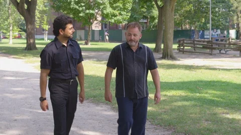 Long Shot - Two men walk down the street while talking and laughing - shot on Stock Footage 124717120