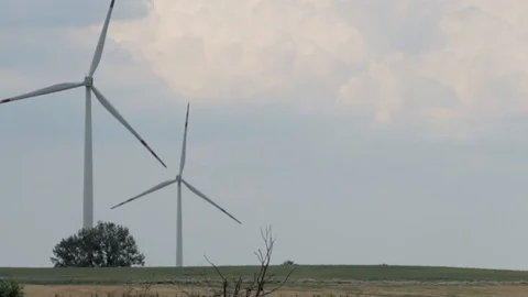 Long shot of two wind mills (turbines) rotating gently in the distance. Stock Footage 99339470