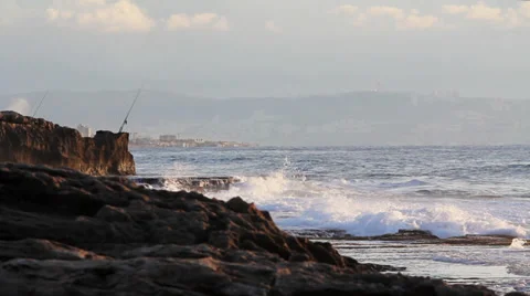 Long shot of waves breaking on a rocky shoreline during sunset Stock Footage 34133770