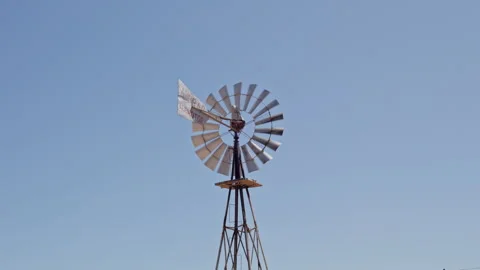 Long shot: Windmill spinning against a blue sky background. UHD 50p Stock Footage 249676044