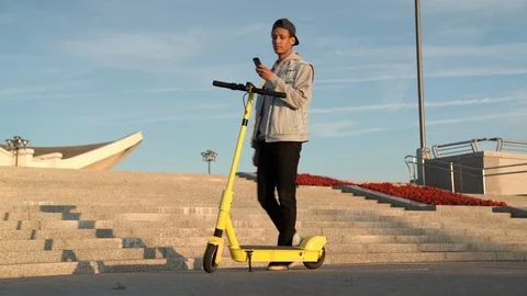 Long shot: Young multi-ethnic guy share electric scooter by smartphone Stock Footage 115995565