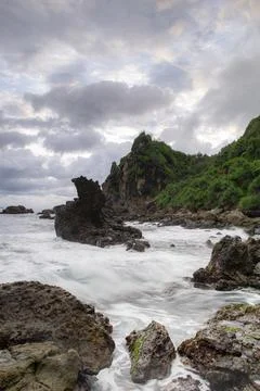 Long shutters of waves crashing against the rocks on a beautiful beach Stock Photos