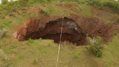 Long slackline stretched over the huge natural pit, a man is walking, 4k Stock Footage 133557784